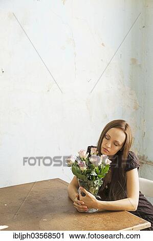 "Young woman sitting at a table with flowers in a vase, Germany, Europe" View Large Photo Image Stock Image - "Young woman sitting at a table with flowers in a vase, Germany, Europe". Fotosearch