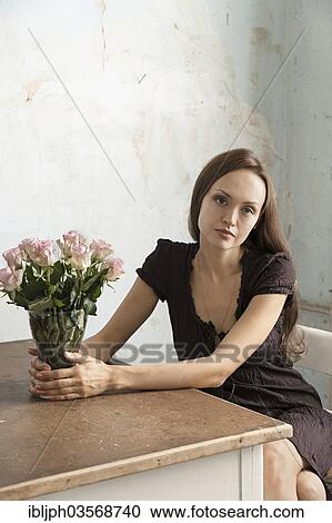 "Young woman sitting at a table with flowers in a vase, Germany, Europe" View Large Photo Image Stock Image - "Young woman sitting at a table with flowers in a vase, Germany, Europe". Fotosearch