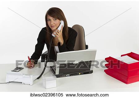 "Young woman sitting at desk with laptop, on the phone" View Large Photo Image Stock Photography - "Young woman sitting at desk with laptop, on the phone". Fotosearch