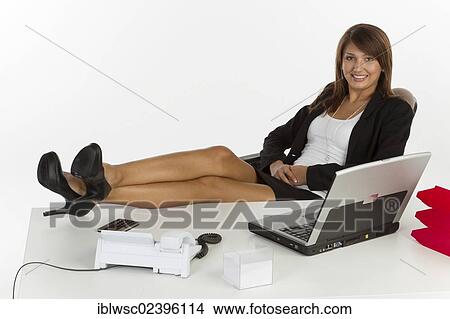 Young woman sitting casually at the desk View Large Photo Image Picture - Young woman sitting casually at the desk. Fotosearch