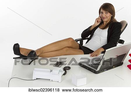 "Young woman sitting casually at the desk, on the phone, smartphone" View Large Photo Image Stock Photo - "Young woman sitting casually at the desk, on the phone, smartphone". Fotosearch