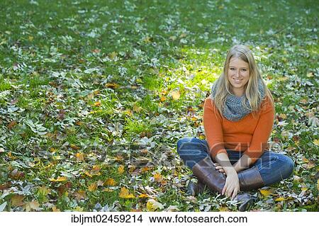 Picture - Young woman sitting cross-legged in the grass. Fotosearch