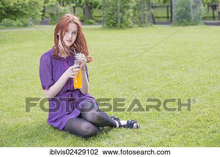 Young woman sitting in a park with a bottle of orange soda View Large Photo Image Stock Image - Young woman sitting in a park with a bottle of orange soda. Fotosearch