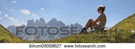 "Young woman sitting on a meadow at Mt Aferer Geisler, Odle Massif or Geisler Group at back, Villnoss, South Tyrol province, Trentino-Alto Adige, Italy, Europe" View Large Photo Image Stock Photo - "Young woman sitting on a meadow at Mt Aferer Geisler, Odle Massif or Geisler Group at back, Villnoss, South Tyrol province, Trentino-Alto Adige, Italy, Europe". Fotosearch