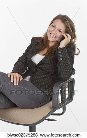 Stock Photo - Young woman sitting on office chair making phone call. Fotosearch