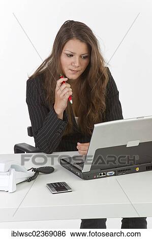 Stock Photograph - Young woman sitting pensively in front of a laptop. Fotosearch
