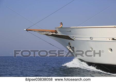 Young woman standing at the bow of a historic yacht and overlooking the sea View Large Photo Image Stock Photo - Young woman standing at the bow of a historic yacht and overlooking the sea. Fotosearch
