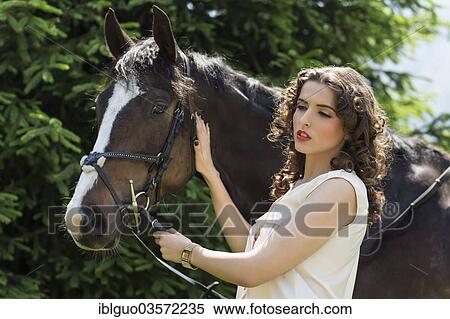 Young woman standing beside a horse View Large Photo Image Stock Photography - Young woman standing beside a horse. Fotosearch