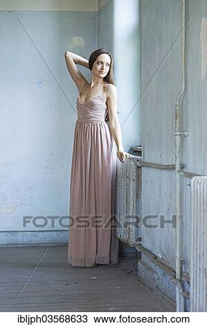 Stock Image - "Young woman standing in a room in need of redecoration, Germany, Europe". Fotosearch