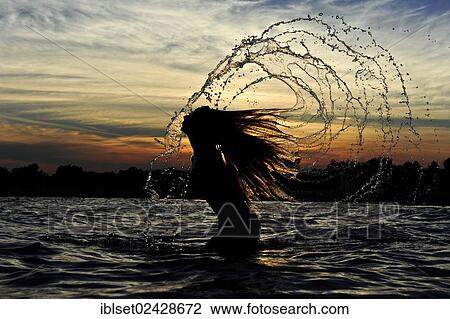 "Young woman standing in the sea throwing back her long hair with splashing water, sunset on the Adriatic Sea, Jesolo, Italy, Europe" View Large Photo Image Stock Image - "Young woman standing in the sea throwing back her long hair with splashing water, sunset on the Adriatic Sea, Jesolo, Italy, Europe". Fotosearch