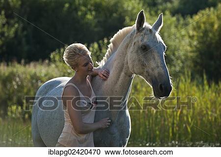 Young woman standing with a Hanoverian horse in a lake View Large Photo Image Stock Image - Young woman standing with a Hanoverian horse in a lake. Fotosearch