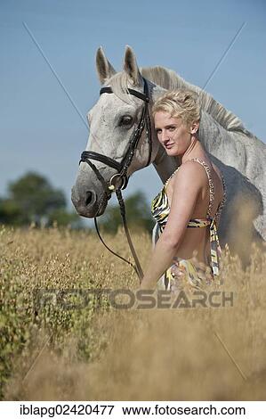 Young woman standing with a Hanoverian horse in a cornfield View Large Photo Image Stock Photo - Young woman standing with a Hanoverian horse in a cornfield. Fotosearch