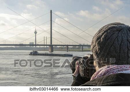 Stock Photograph - "Young woman taking photographs of the Rhine, Dusseldorf, Rhineland, North Rhine-Westphalia, Germany, Europe". Fotosearch