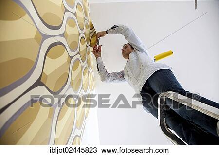 Young woman wallpapering a wall View Large Photo Image Stock Image - Young woman wallpapering a wall. Fotosearch