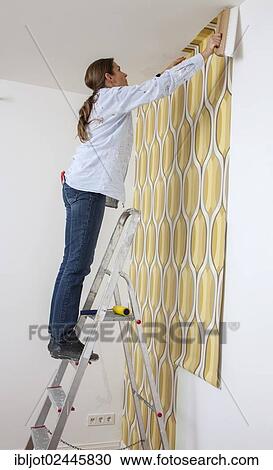 Young woman wallpapering a wall View Large Photo Image Stock Image - Young woman wallpapering a wall. Fotosearch