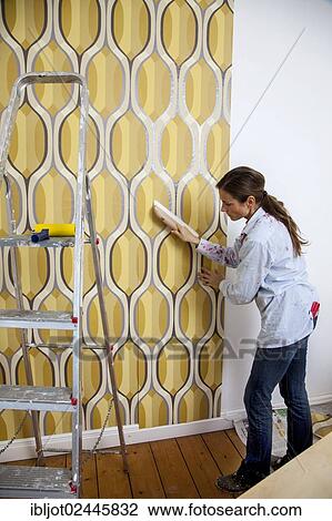 Young woman wallpapering a wall View Large Photo Image Stock Image - Young woman wallpapering a wall. Fotosearch