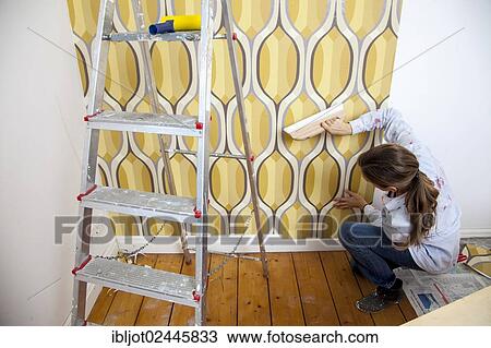 Young woman wallpapering a wall View Large Photo Image Stock Image - Young woman wallpapering a wall. Fotosearch