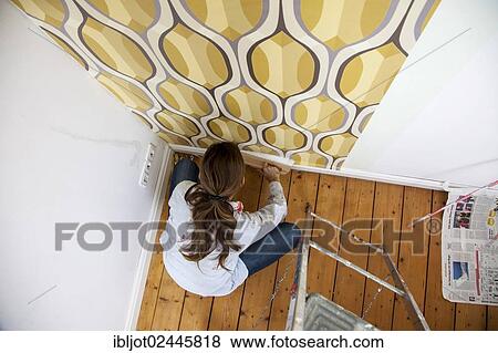 Young woman wallpapering a wall View Large Photo Image Stock Photo - Young woman wallpapering a wall. Fotosearch