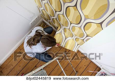 Young woman wallpapering a wall View Large Photo Image Stock Photo - Young woman wallpapering a wall. Fotosearch