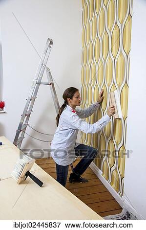 Young woman wallpapering a wall View Large Photo Image Stock Photo - Young woman wallpapering a wall. Fotosearch