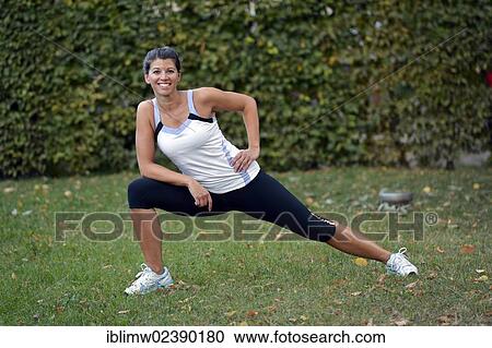 Stock Image - "Young woman warming up, stretching exercises, Stuttgart, Baden-Wuerttemberg, Germany, Europe, PublicGround, Europe". Fotosearch