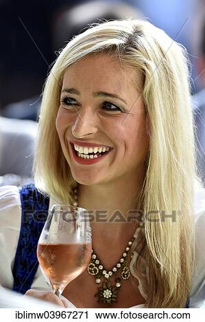 Stock Image - "Young woman wearing a dirndl dress holding a wine glass, smiling, Stuttgart, Baden-Wurttemberg, Germany, Europe". Fotosearch