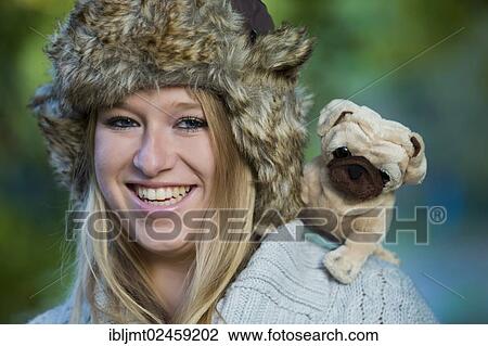 Young woman wearing a fur hat with a plush pug on her shoulder View Large Photo Image Stock Image - Young woman wearing a fur hat with a plush pug on her shoulder. Fotosearch