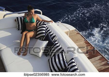 Stock Photography - "Young woman wearing a green bikini sitting on the rear deck of a motor yacht, French Riviera, Cote d'Azur, Mediterranean Sea, Europe". Fotosearch
