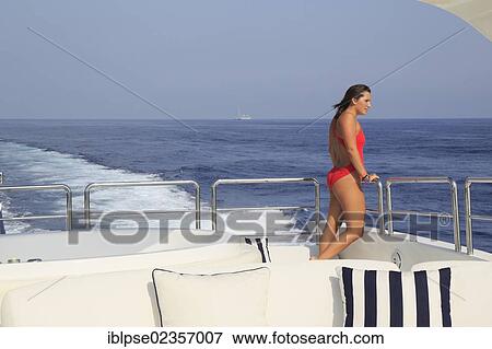 "Young woman wearing a red swimsuit standing on the back deck of a moving motor yacht, French Riviera, Cote d'Azur, Mediterranean Sea, Europe" View Large Photo Image Stock Photo - "Young woman wearing a red swimsuit standing on the back deck of a moving motor yacht, French Riviera, Cote d'Azur, Mediterranean Sea, Europe". Fotosearch
