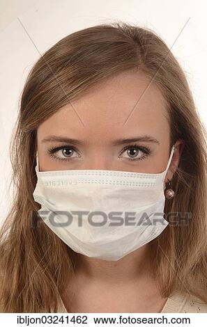 Stock Image - Young woman wearing a surgical mask. Fotosearch