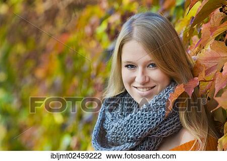 Young woman wearing a thick scarf in front of colourful autumn leaves View Large Photo Image Stock Image - Young woman wearing a thick scarf in front of colourful autumn leaves. Fotosearch