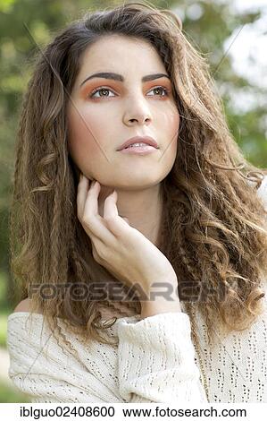 Stock Image - "Young woman wearing a white sweater, portrait, outdoors". Fotosearch