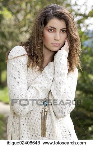 Stock Photo - "Young woman wearing a white sweater, outdoors". Fotosearch