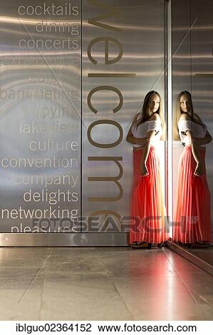 Stock Image - Young woman wearing a white top and a long red skirt. Fotosearch