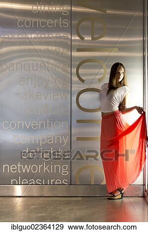 Stock Photo - Young woman wearing a white top and a long red skirt. Fotosearch