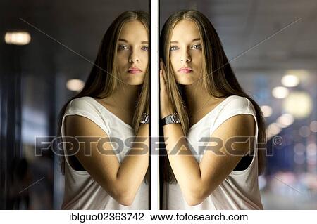 Stock Image - "Young woman wearing a white top, mirror image". Fotosearch