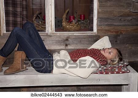 Young woman wearing a winter outfit lying on the bench in front of a hiking hut View Large Photo Image Stock Image - Young woman wearing a winter outfit lying on the bench in front of a hiking hut. Fotosearch