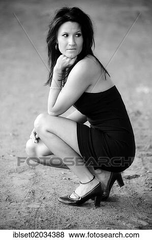 "Young woman wearing black dress, squatting with her chin supported on her fist" View Large Photo Image Stock Photo - "Young woman wearing black dress, squatting with her chin supported on her fist". Fotosearch