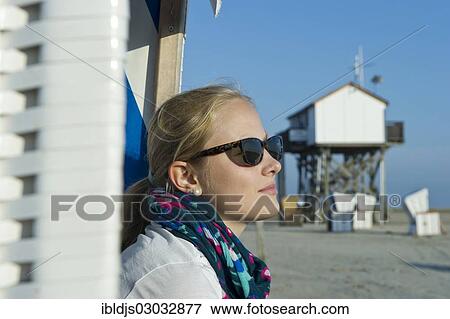 "Young woman wearing sunglasses on the beach in front of a house on stilts, St Peter-Ording, Schleswig-Holstein, Germany, Europe" View Large Photo Image Stock Photo - "Young woman wearing sunglasses on the beach in front of a house on stilts, St Peter-Ording, Schleswig-Holstein, Germany, Europe". Fotosearch