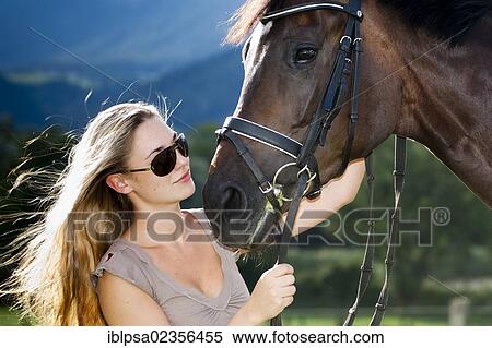 Stock Photography - "Young woman wearing sunglasses cuddling with a horse, Hanoverian, bay, North Tyrol, Austria, Europe". Fotosearch