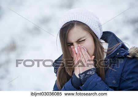 Stock Photography - "Young woman wearing winter clothes blowing her nose, Germany, Europe". Fotosearch