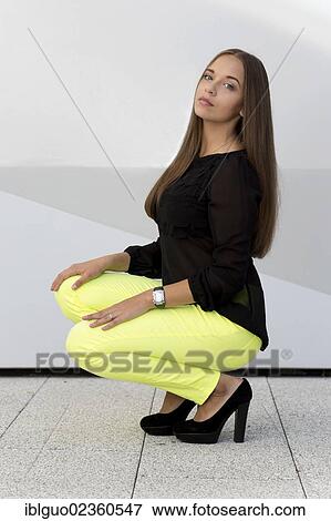 Stock Photo - "Young woman with a black top, bright yellow trousers and black high heels". Fotosearch