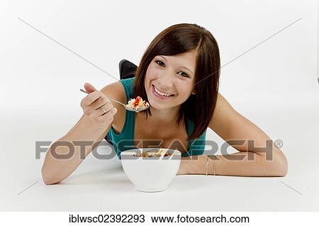 Stock Image - Young woman with a bowl of cereal. Fotosearch