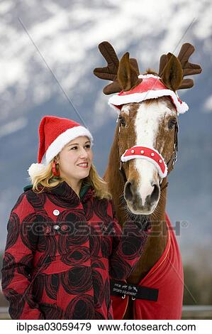 Stock Photo - "Young woman with a Christmas hat and a horse with Christmas reindeer antlers, Pill, North Tyrol, Austria, Europe". Fotosearch