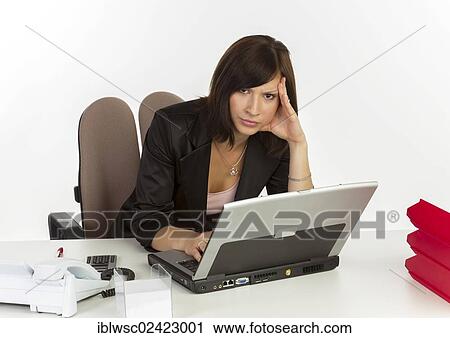 Stock Image - Young woman with a laptop sitting at a desk. Fotosearch