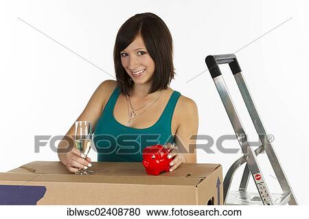 "Young woman with a moving box, a piggy bank and a glass of champagne in her hand" View Large Photo Image Stock Image - "Young woman with a moving box, a piggy bank and a glass of champagne in her hand". Fotosearch
