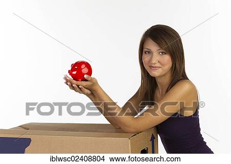 "Young woman with a moving box, holding a piggy bank in her hands" View Large Photo Image Picture - "Young woman with a moving box, holding a piggy bank in her hands". Fotosearch