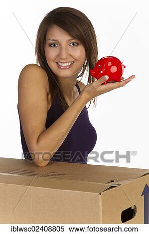 "Young woman with a moving box, holding a piggy bank in her hand, smiling" View Large Photo Image Stock Photography - "Young woman with a moving box, holding a piggy bank in her hand, smiling". Fotosearch