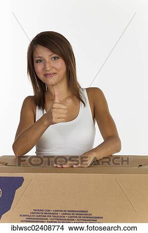 "Young woman with a moving box, making a thumbs-up gesture" View Large Photo Image Picture - "Young woman with a moving box, making a thumbs-up gesture". Fotosearch