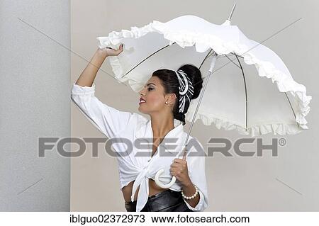 "Young woman with an updo hairstyle, wearing a white shirt and holding a white umbrella" View Large Photo Image Stock Image - "Young woman with an updo hairstyle, wearing a white shirt and holding a white umbrella". Fotosearch